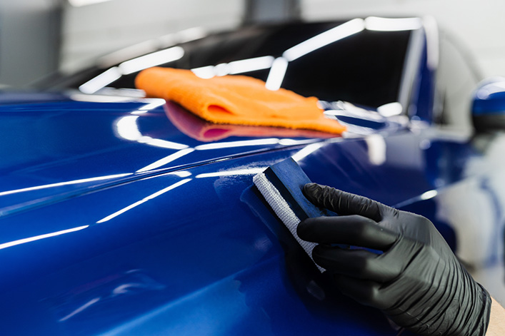 Applying ceramic protective coat to blue car